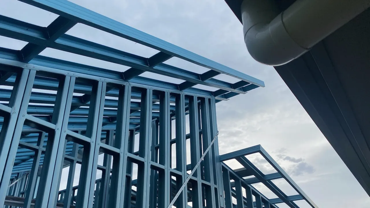 Blue steel framing of a shed house against a cloudy sky, showcasing modern architectural design.